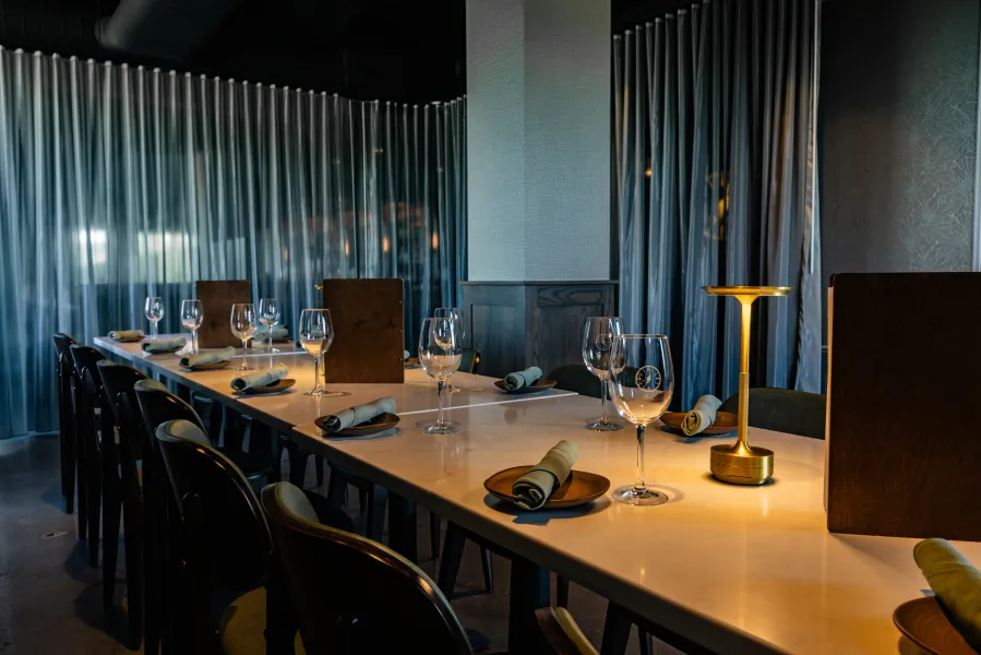 A dimly lit elegant private dining space with a large clock window.